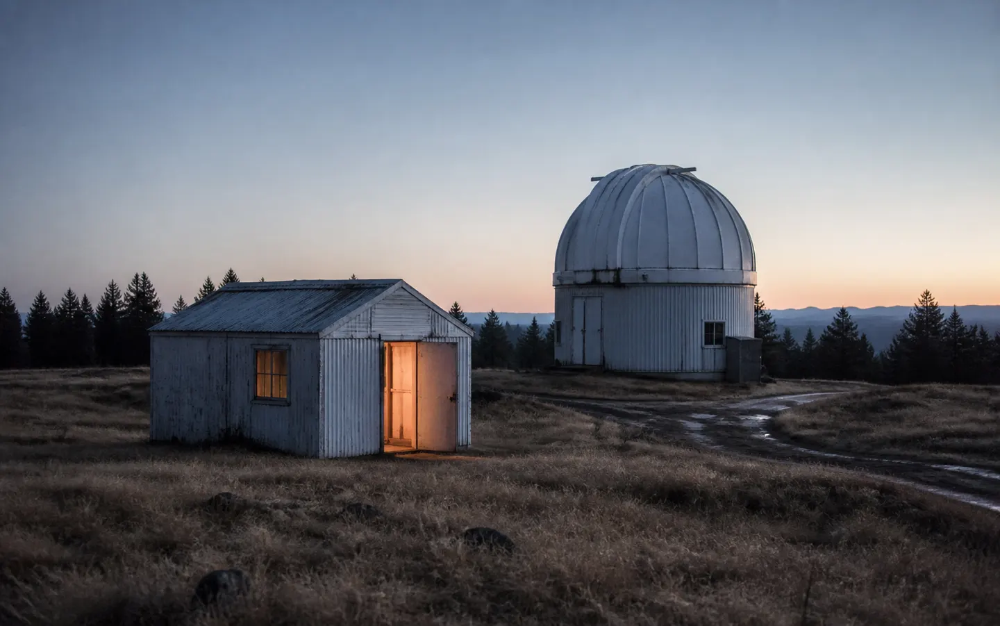 An observatory dome and small instrument shed before sunrise